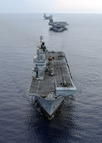 The Royal Navy Invincible-class aircraft carrier HMS Illustrious, and Nimitz-class aircraft carriers USS Harry S Truman and USS Dwight D Eisenhower transit in formation during a multi-ship maneuvering exercise in the Atlantic Ocean